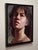 This oil painting on linen panel captures a contemplative figure, bathed in soft, natural light that accentuates the...