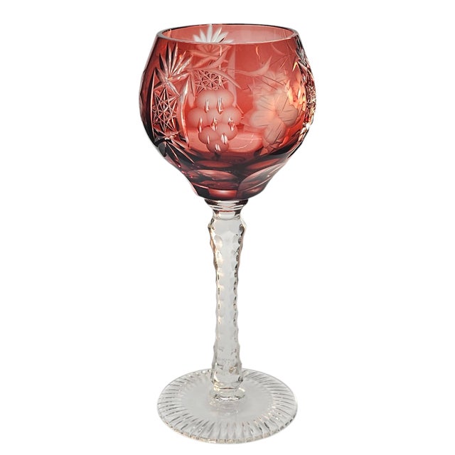 In rose red, the glass blooms with grapes and flowers, each motif cut sharp and clear against its crystal body. The bowl...