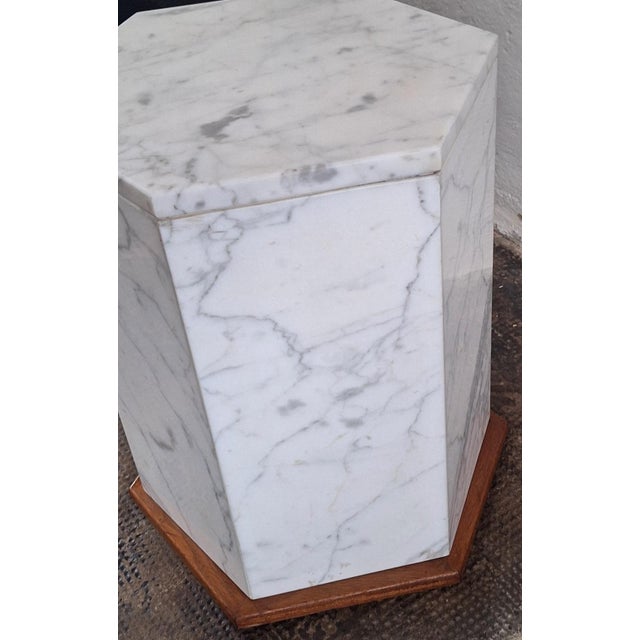 Sleek and elegant Italian Carrera marble monolith pedestal side table, finely veined marble on a wood base. The hollow...