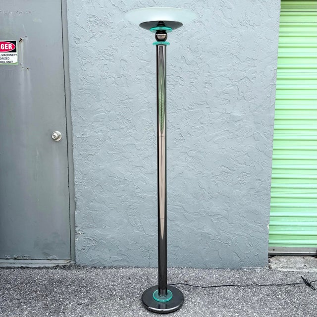 A striking vintage Postmodern torchiere floor lamp featuring a tall, streamlined profile with a reflective dark metal...