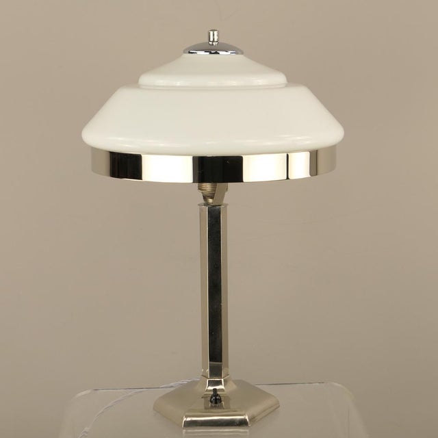Table lamp with chromed hexagonal base, tiered white opal glass shade. This piece has an attribution mark, I am sure that...