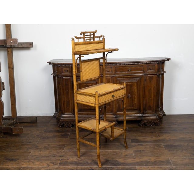 An English bamboo freestanding shelf from the early 20th century, with rattan accents and single drawer. Created in...