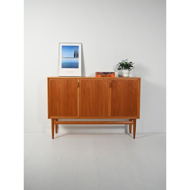Highboard with oak frame and flamed teak doors. Three doors with curved oak handles, light lines. Highboard with oak frame...