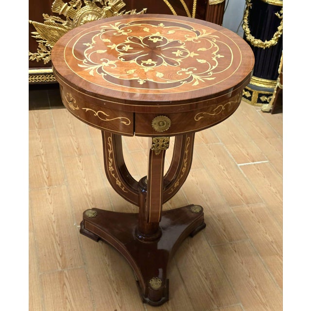 Bring timeless European elegance into your home with this exquisite French Empire style round accent table. Featuring a...