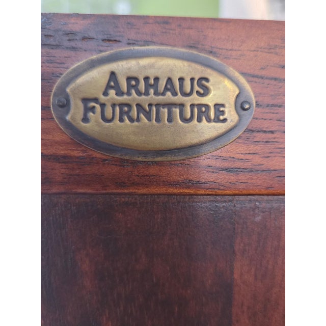 A substantial Arhaus solid wood secretary desk, showcasing classic proportions, rich warm wood tones, and refined brass...