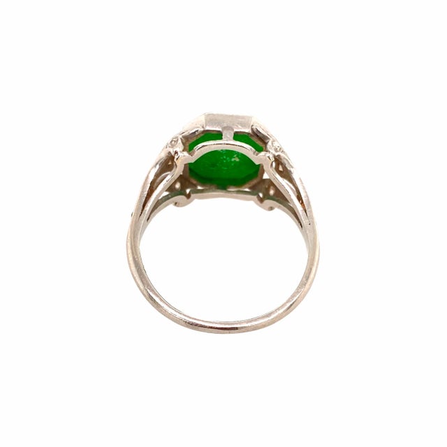 A fine and beautiful Edwardian platinum, diamond, and jade ring, circa 1900. The octagonal jade is a flat cut in a...