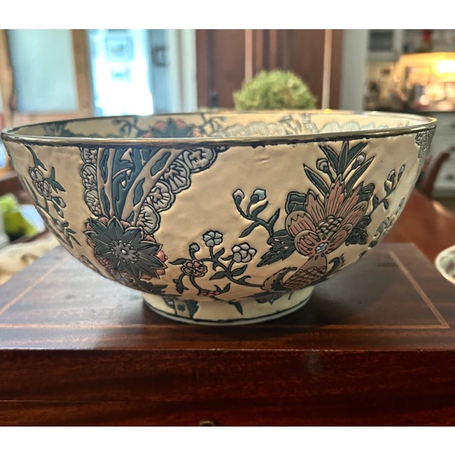 Mid 20th Century ceramic Asian bowl with decorative floral pattern in shades of blue and pink. Metal band around rim.