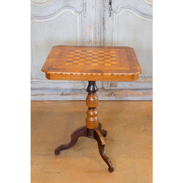 An Italian walnut, mahogany and ash game side table from the 19th century with marquetry top, turned pedestal and carved...