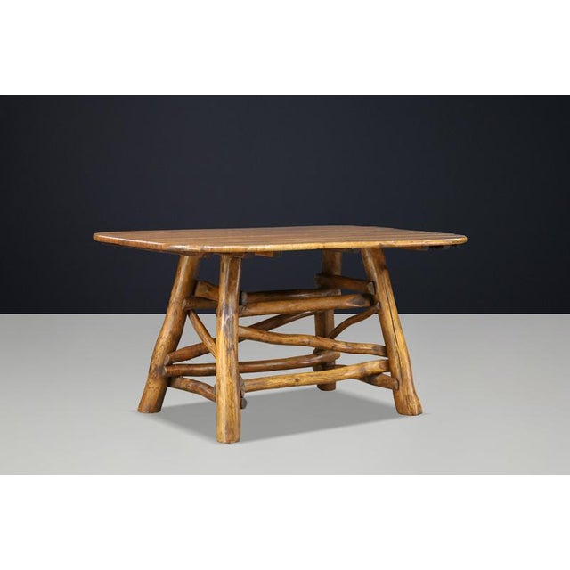 A distinctive wooden dining table from the 1950s, featuring a rounded rectangular plank top and an expressive base...