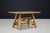 A distinctive wooden dining table from the 1950s, featuring a rounded rectangular plank top and an expressive base...