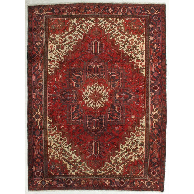 Vintage hand-knotted Persian Heriz wool rug with a red field centered by a large geometric medallion in navy, ivory, and...