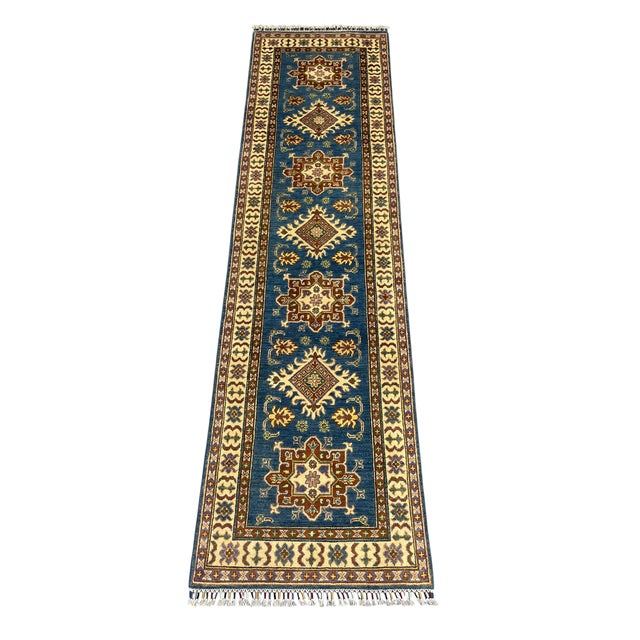 A rich blue field gives this natural-dyed wool runner a striking backdrop for its alternating tribal medallions. Cream and...