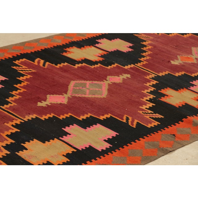 Handwoven in a wool flat weave originating circa 1910-1920, this antique Kilim rug connotes a Northwest Persian Kilim...