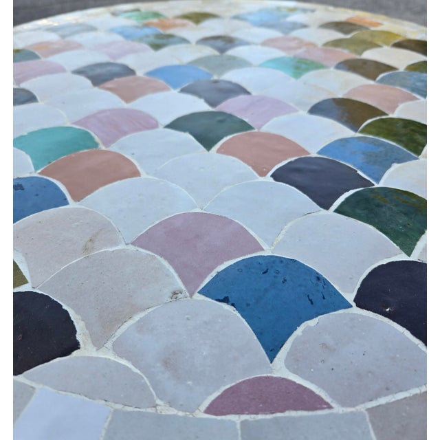 Beautiful round mosaic tile table featuring a vibrant multicolor tiled top and durable black wrought-iron style base. The...