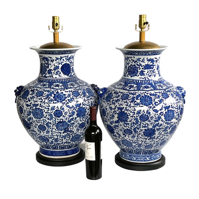 each imposing lamp with everted neck above a tapering body painted overall with bold meandering floral and foliate vines...