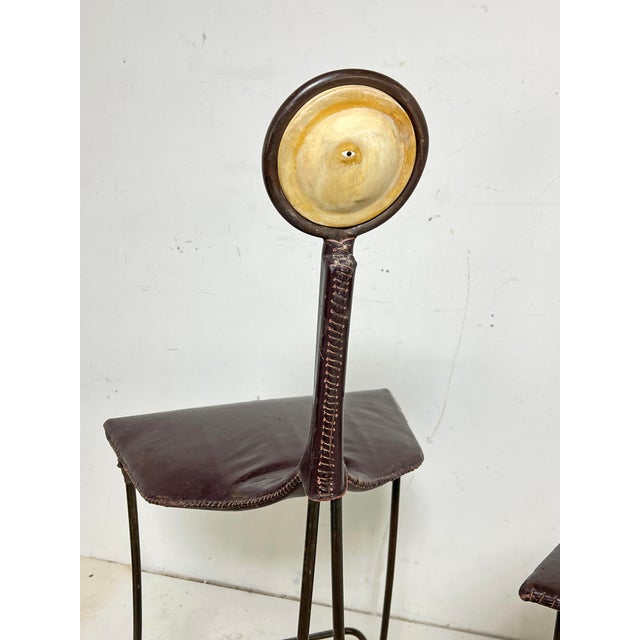 A set of three postmodern Brazilian bar stools, ca. 1980s, in leather and wrought iron with ceramic rondelle faces inset...