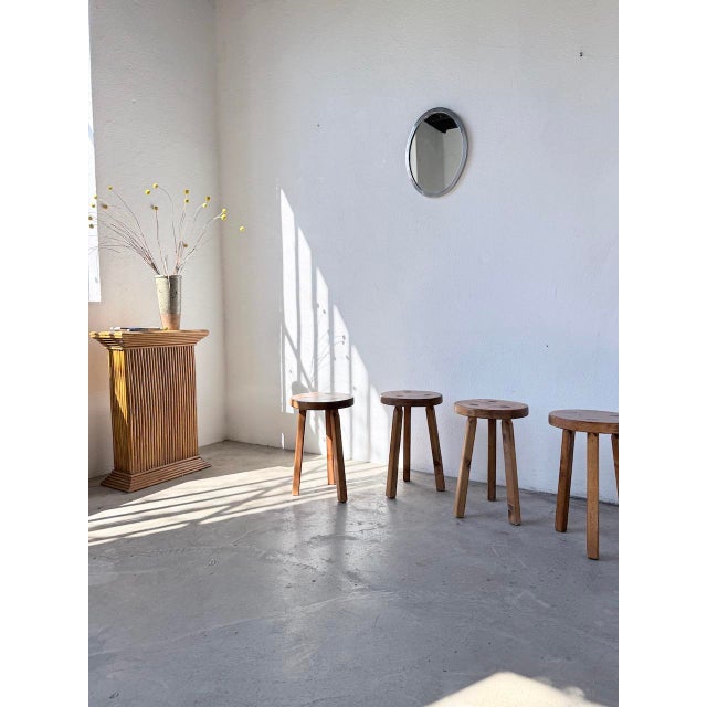 Set of four 1950s tripod stools in pine, in a mountain furniture style. Their round, thick seats, resting on slightly...