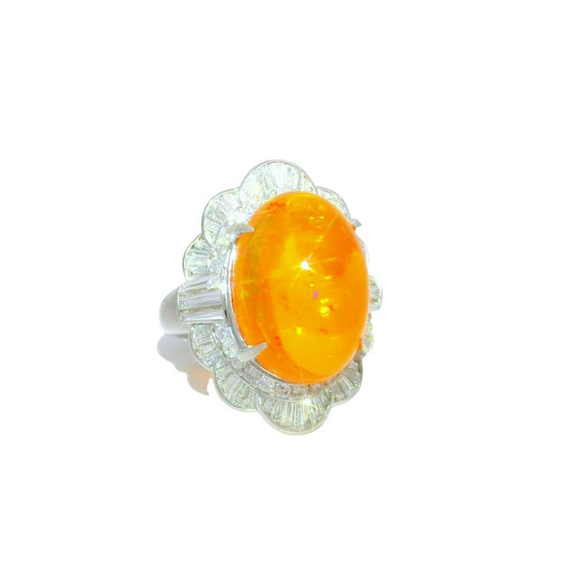 A striking and elegant dome ring crafted in platinum. It features a 9.52-carat cabochon fire opal with a vibrant orange...