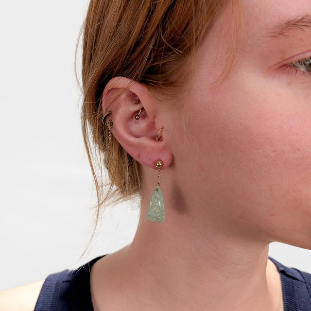 A fine pair of vintage gold & jade earrings. In 14 karat yellow gold. Each with a carved jadeite drop mounted on a hook...