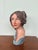 This sculpture is a female bust created in a style reminiscent of 20th-century polychrome terracotta or ceramic works. The...