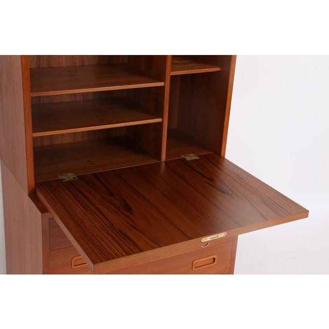 The Hundevad bookcase consists of a lower module with drawers and an upper module with a writing surface and doors. Behind...