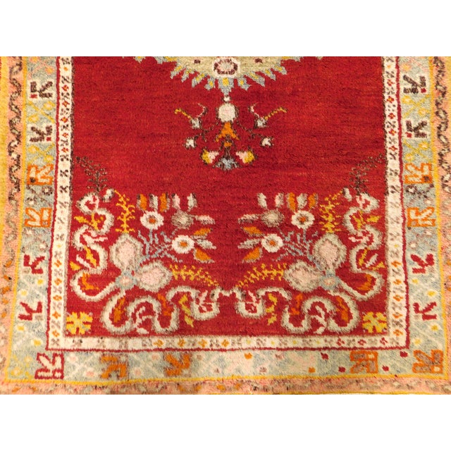 Striking central medallion, surrounded by floral decoration on a red field. Border displaying geometric motifs on a soft...