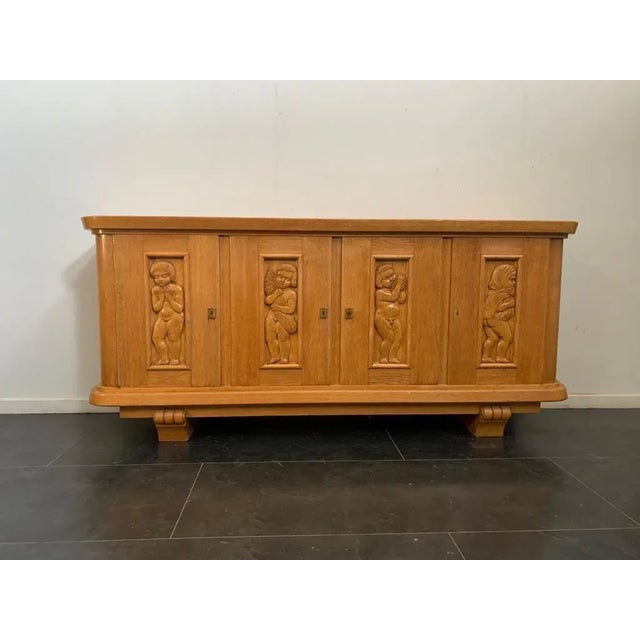 Sideboard in solid ash wood, with finely carved panels with putti that identify the 4 seasons. Rosewood interior. Hinges,...