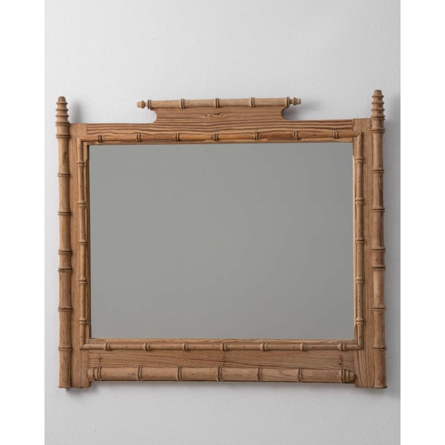 A circa 1900 French wall mirror crafted in carved wood and designed in the faux bamboo style. The frame imitates bamboo...