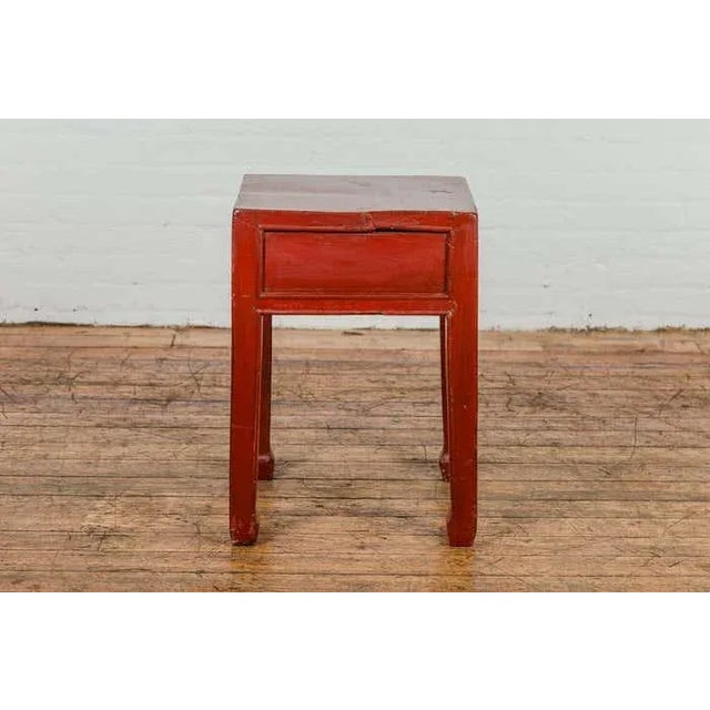 A late Qing Dynasty period red lacquer wooden side table from the early 20th century with single drawer and horse hoof...