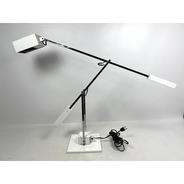 An iconic 1970's articulating chrome and white metal desk lamp designed by Robert Sonneman. The counter-balanced light is...