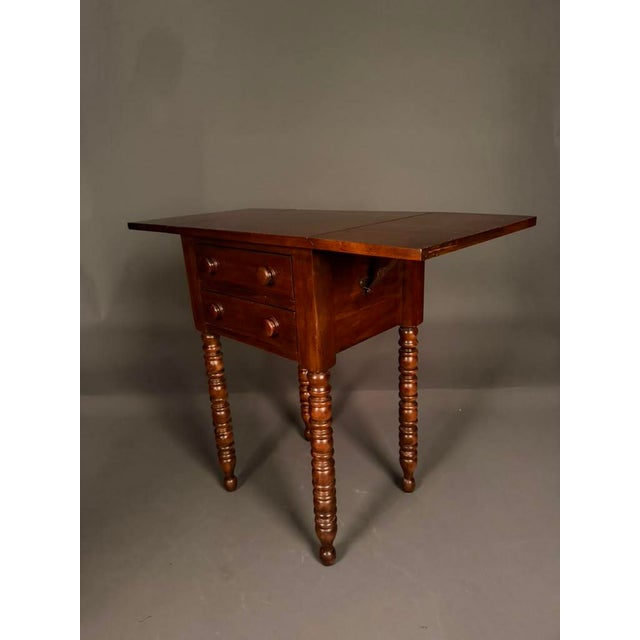 Beautifully crafted by the Davis Cabinet Company of Nashville, Tennessee, this American-made drop leaf side table...