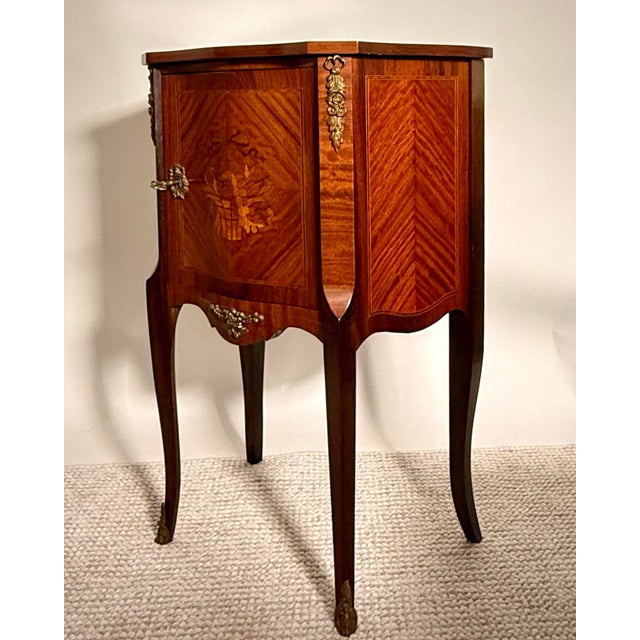 Elegant French Louis XV-style side cabinet crafted in mahogany with finely figured veneers, floral marquetry inlay, and...