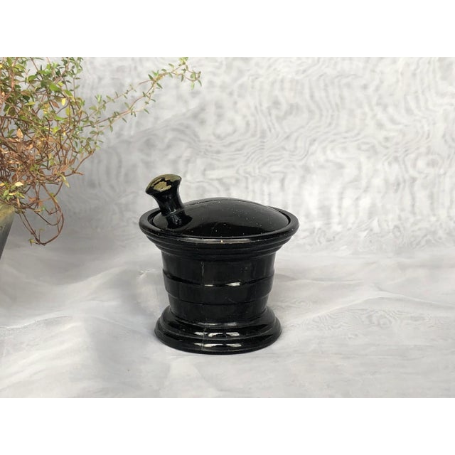Molded into the shape of a mortar and pestle, this vintage black amethyst agate glass jar once held a Jean Vivadou perfume...