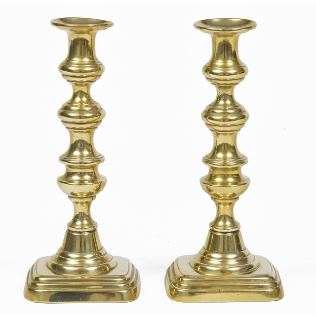 Pair of Victorian cast brass candlesticks with turned column on a rectangular stepped base.