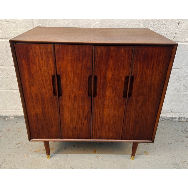 Striking mid-century modern cabinet crafted in richly grained wood, featuring clean Scandinavian-inspired lines and...