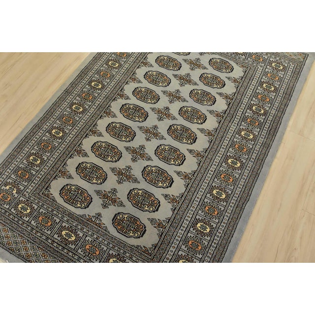 A tribal Bokhara rug hand-knotted with fine wool on a cotton foundation. This rug features rows of repeating medallions...