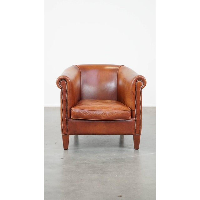 This comfortable cognac-colored cowhide club chair with a correct finish with decorative nails in English style. This...