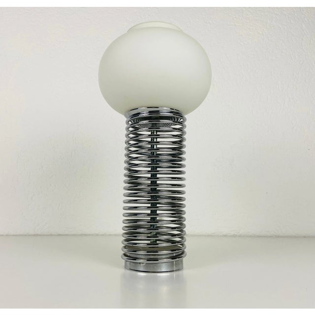 Extraordinary table lamp made in Italy in the 1960s. It is fascinating with its opal glass stuck on the chrome body....