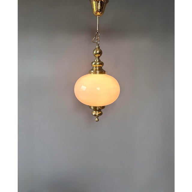 A sophisticated vintage pendant lamp featuring a beautifully proportioned white opal glass globe suspended within an...