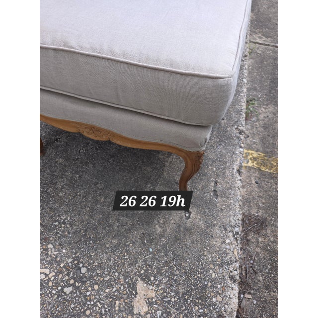 Traditional French provential style Ottoman with tan colored linen fabric.
