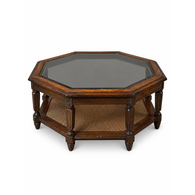 A distinctive vintage hexagonal coffee table combining warm wood tones, a smoked-glass inset top, and a woven cane lower...