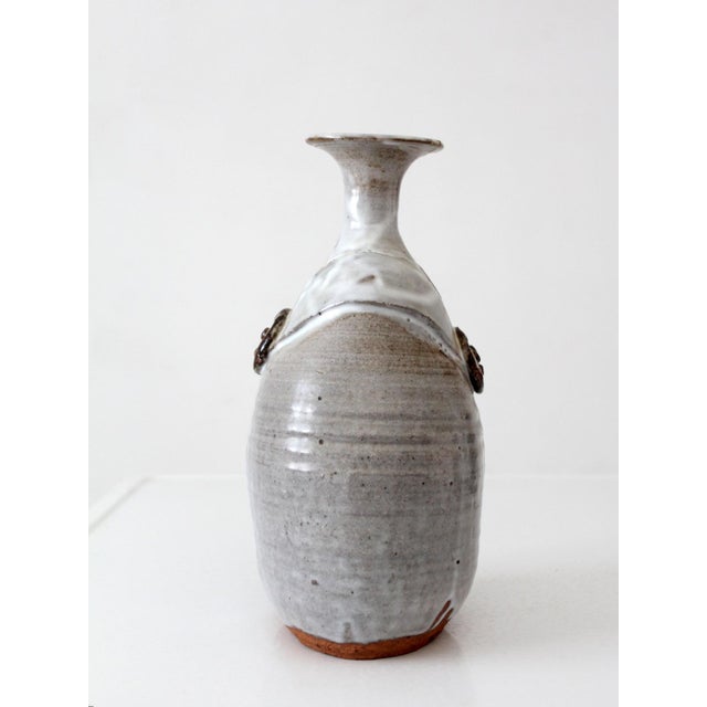 This vintage studio pottery vase features a rounded, sculptural body with a narrow flared neck, showcasing refined...