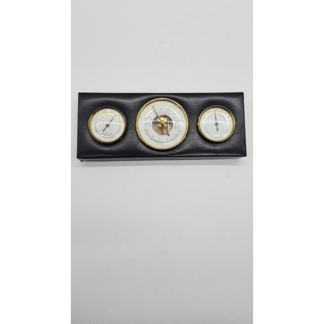 A classic wall-mounted weather station from the mid-20th century, made in an elegant rectangular case covered with black...