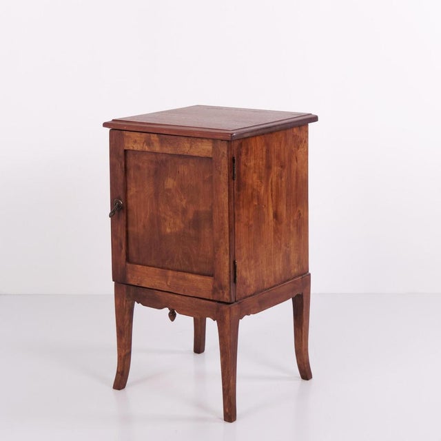 Bedside table crafted in dark wood with brass mounts and elegant tapered legs. Dating from the 1940s, it offers practical...
