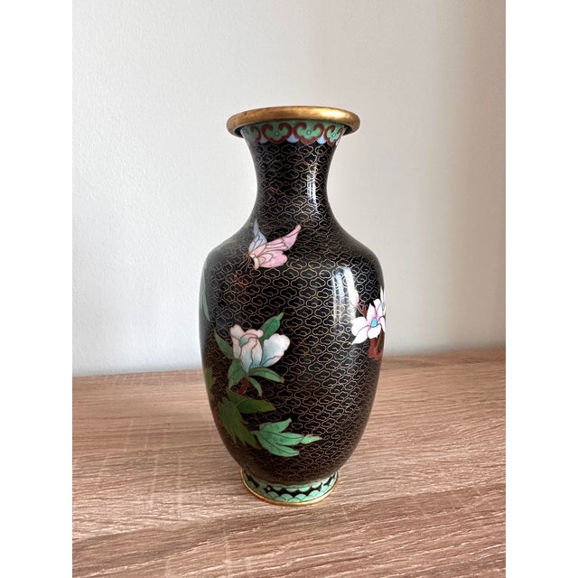 A beautifully detailed vintage Chinese cloisonné enamel vase featuring colorful peonies, delicate butterflies, and...