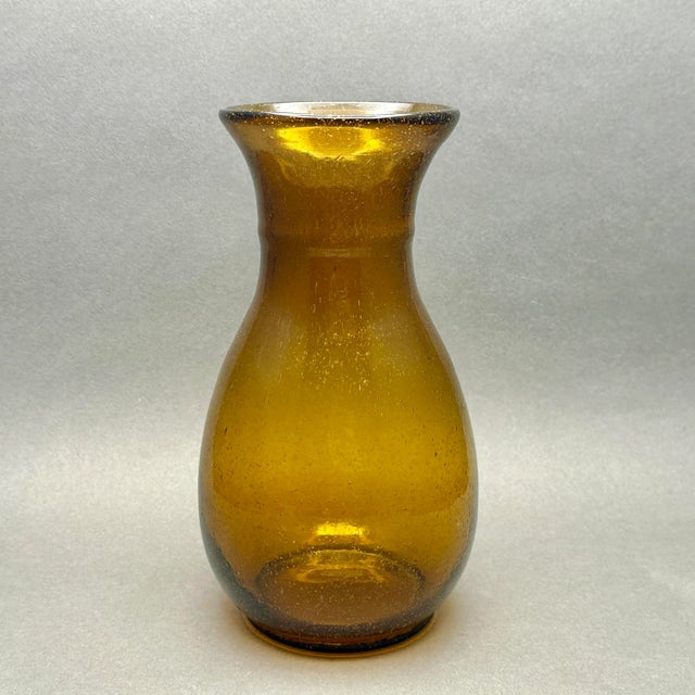 Vintage hand blown amber glass vase. It has a minimalist MCM form with tiny bubbles detail in the glass. It measures...