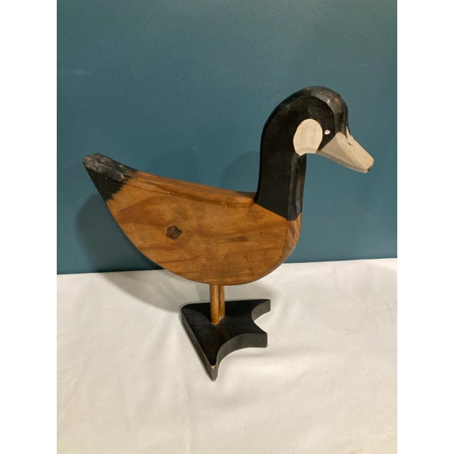Hand carved wooden duck sculpture signed and dated 1983. This folk art piece features a stylized bird form with painted...