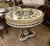 Create an extraordinary dining space with this grand French-inspired round dining table, featuring an elegant white...