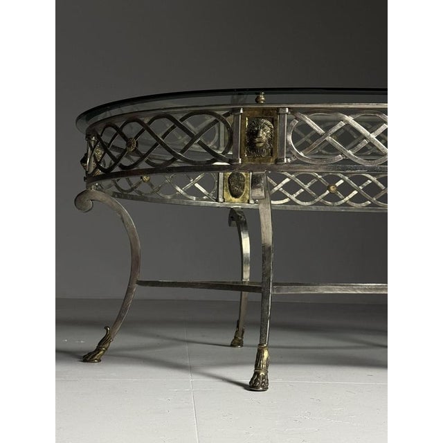 Oval vintage coffee table. Silver-colored metal base with a beveled glass top. Empire / Regency style. Characteristic...