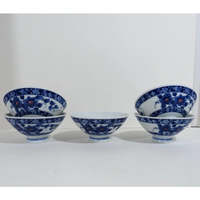 Thin porcelain rice bowls in blue and pink floral and detailed stripe decoration on white glaze. The set of five are...
